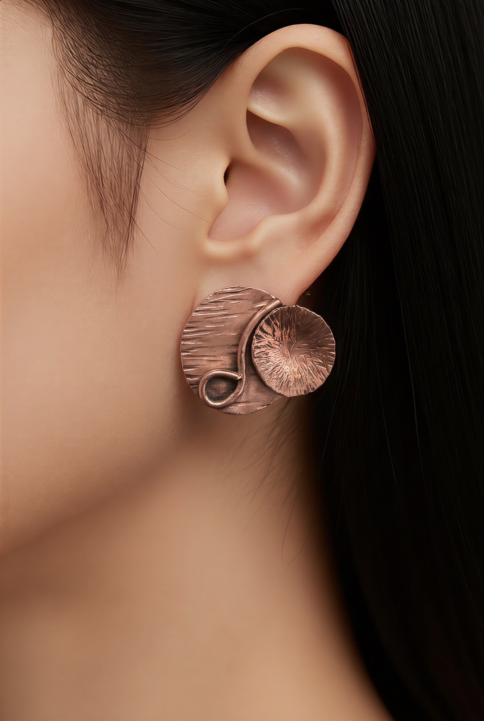 Woman wearing handmade layered assymetrical copper stud earrings by Ginny Taylor Designs - one-of-a-kind artisan copper jewelry